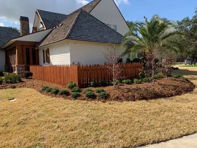 Finished curved bed with shrubs, mulch and a cedar fence