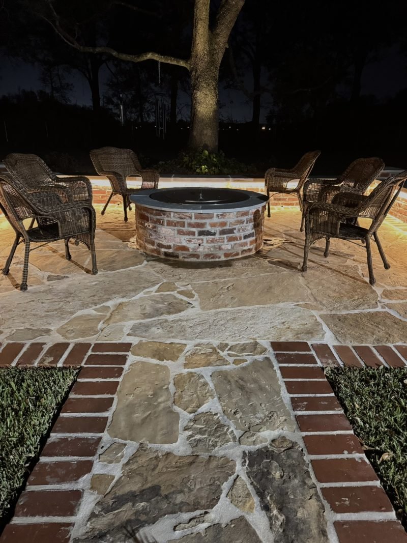 Fire pit with wicker chairs on a flagstone patio, seat walls lit from below